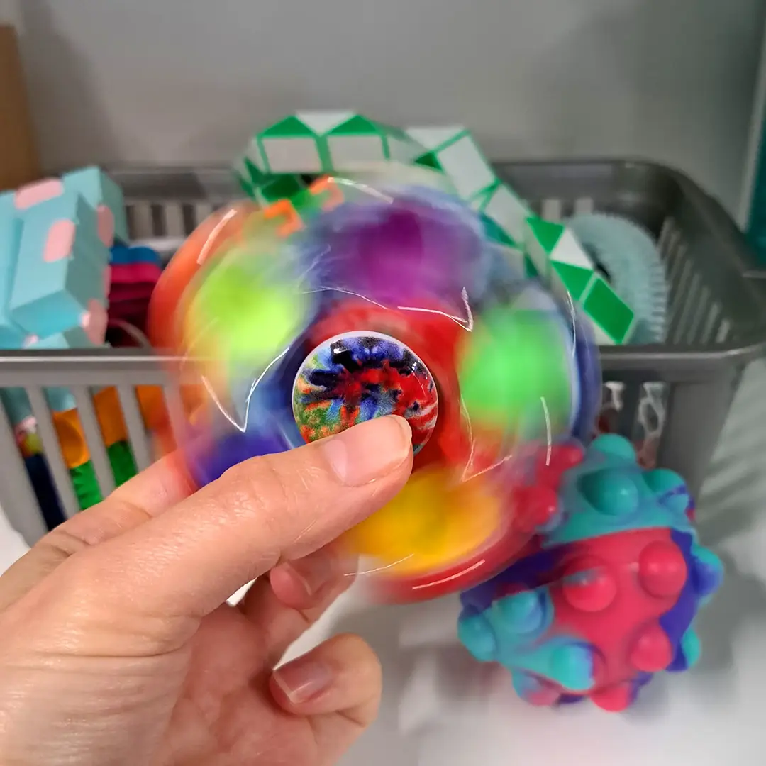 A fidget toy is spinning in someone's fingers, blending a rainbow array of colours.